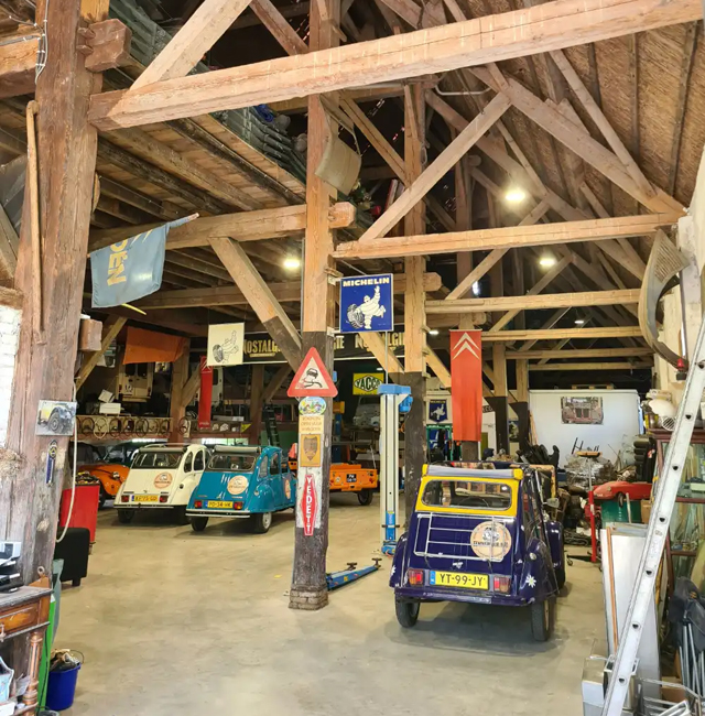 De schuur van eendverhuur info met diverse vintage auto's en automobilia bij 2CV Hoeve Waterrijk