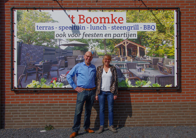 Eigenaren van 't Boomke voor een reclamebord van hun restaurant