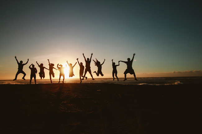 Groep vrienden geniet van zonsondergang op het strand bij Strandpaviljoen FF Tijd in Hoek van Holland