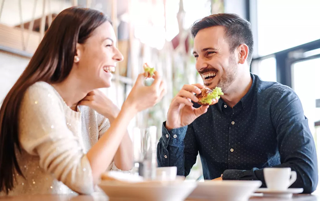 een stel geniet van een lunch in de buren lachend en ontspannen.